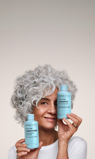 Silvina holding shampoo and conditiioner bottles on her face
