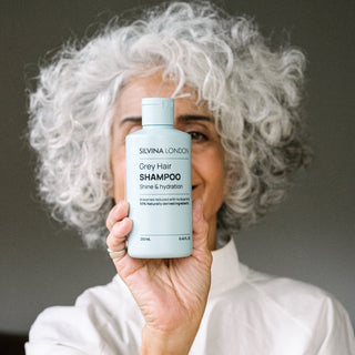 Silvina holding a bottle of Silvina London GREY Hair Shampoo with a neutral background
