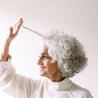 Silvina holding a strand of Grey hair against a white background